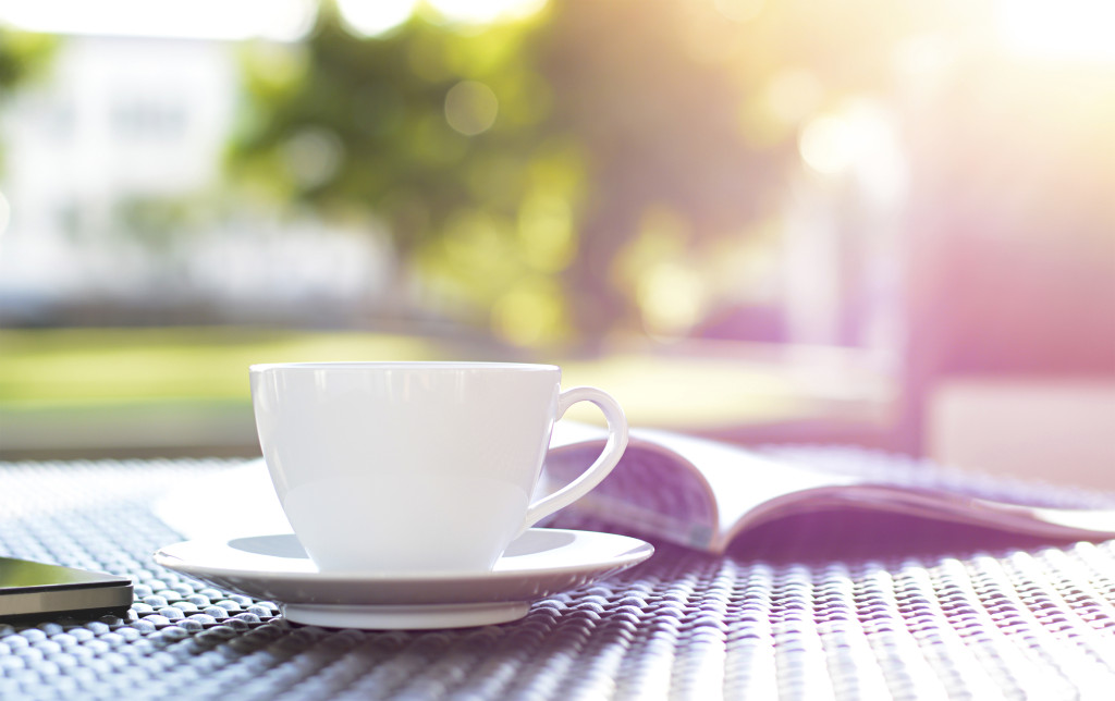 Coffee cup with book on blurred green nature background - chill