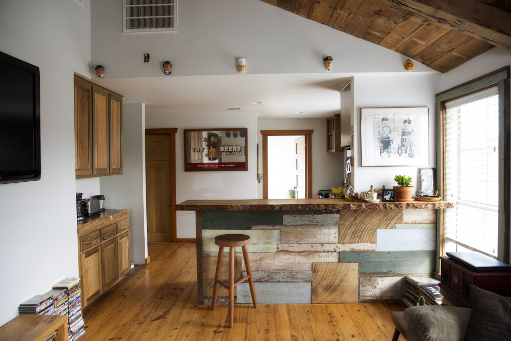 Looking into the kitchen, the breakfast bar makes a statement with its eclectic mix of salvaged wood. The tiny figurines hanging near the ceiling are from England and were passed down to Taylor by her grandmother. 