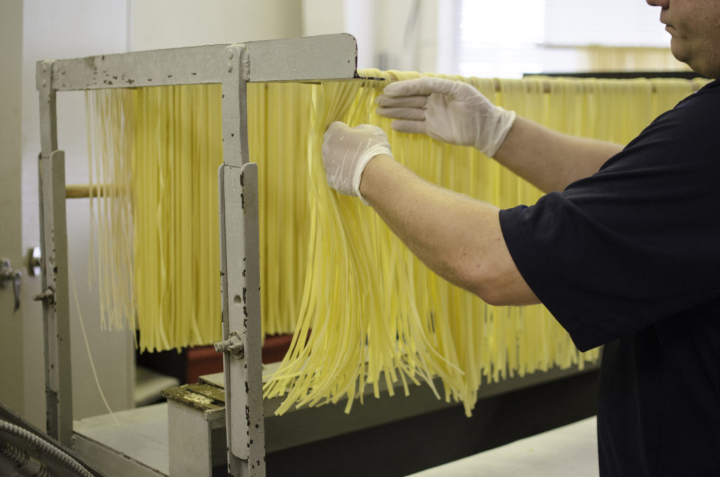 Thompson hangs the fresh pasta on bamboo racks after cutting them.