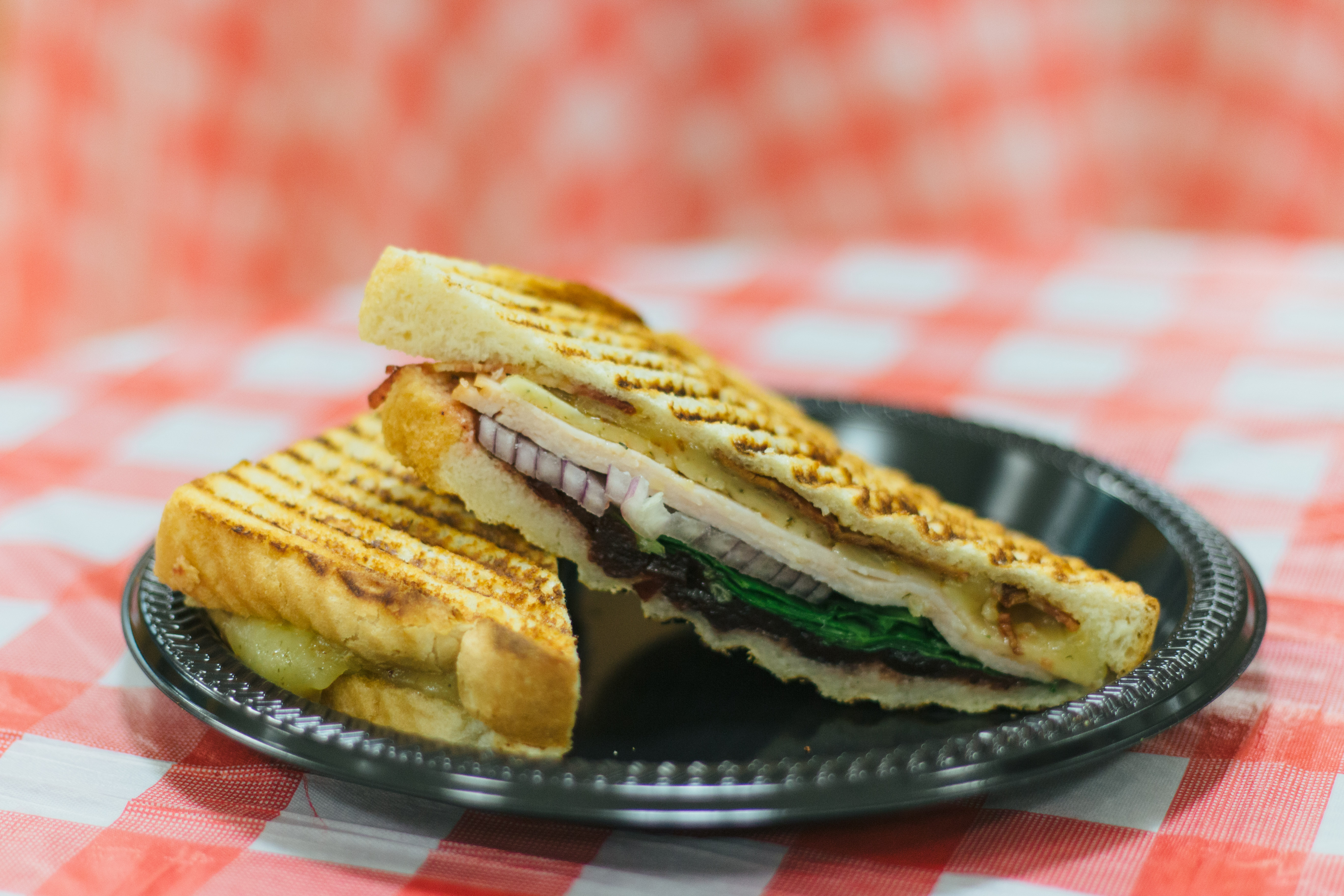 Turkey bacon and Havarti panini from Ma Rouge's Pizza & Paninis, featuring sliced turkey breast, applewood bacon and Havarti cheese dressed with red onions, spinach and cranberry, served on sourdough bread.