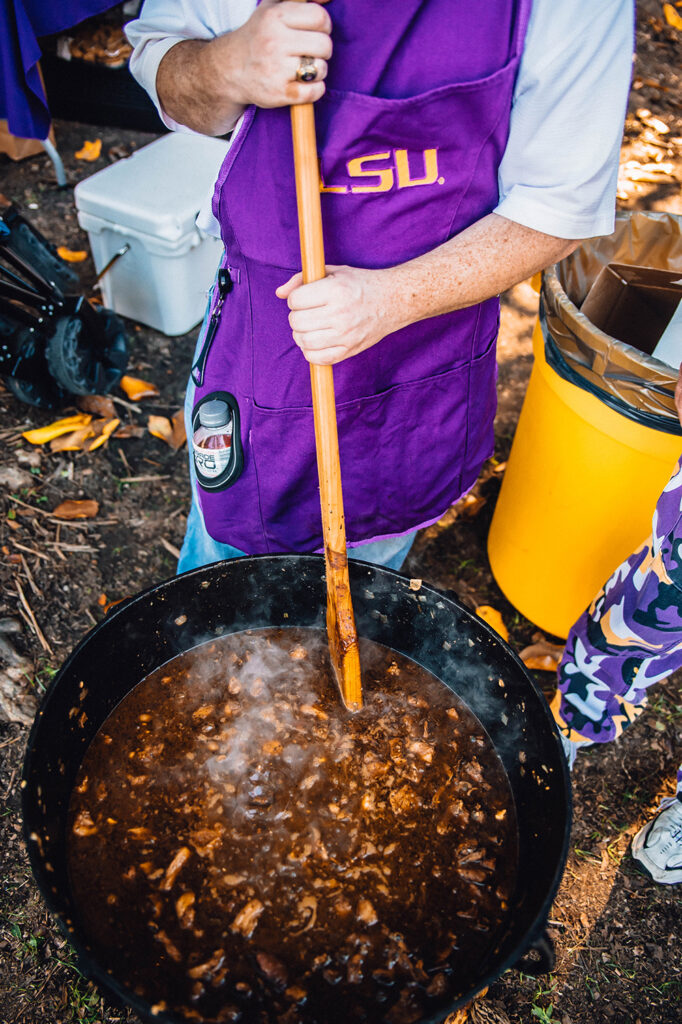 Close up on tailgater stirring a large pot of gumbo
