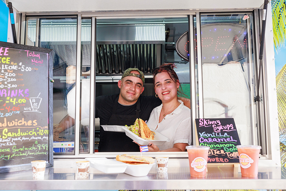Elisa’s Cuban Coffee and Kitchen owners Jose Peña and Elisa Valera peaking out of the food truck